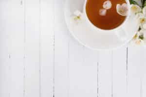 A cup of green tea with jasmine on a white surface